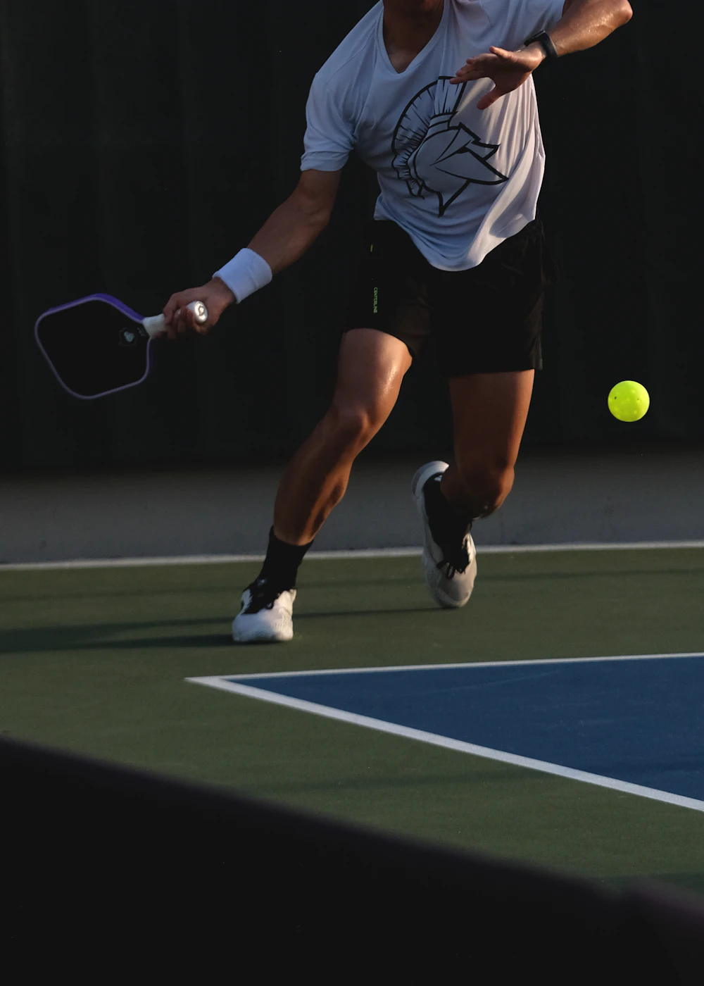A player reaching for a shot mid-rally on an indoor court